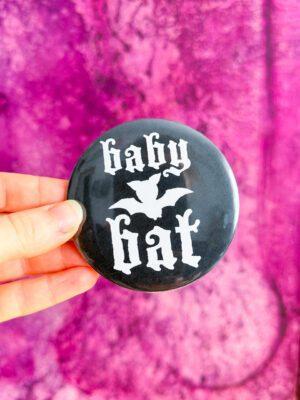 Duża przypinka do przypięcia na torbę z nietoperzem i napisem baby bat w kolorze czarno-białym.