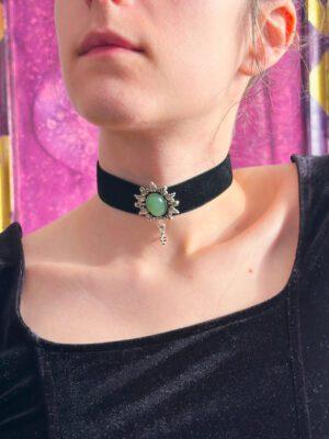 Czarna obróżka z weluru z zielonym awenturynem w ozdobnej, roślinnej oprawie. Założona na szyi modelki.