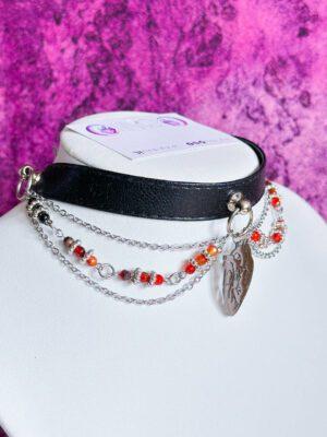Czarny choker z ekoskóry z anatomicznym sercem, stalowymi łańcuszkami oraz czerwonymi i czarnymi koralikami w stylu gotyckim.